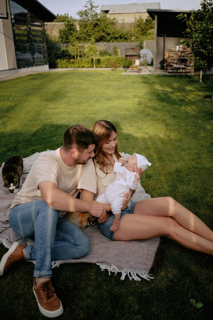 happy couple sat with their baby in their garden