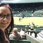 Lady taking a selfie at wimbledon looking over the tennis court and crowd