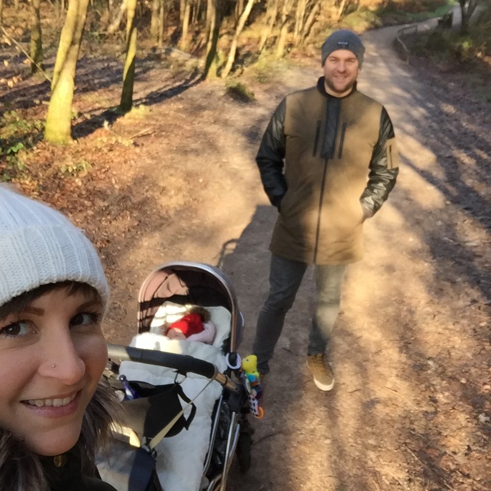 Mum and dad walking in a woods with their baby in pram in winter